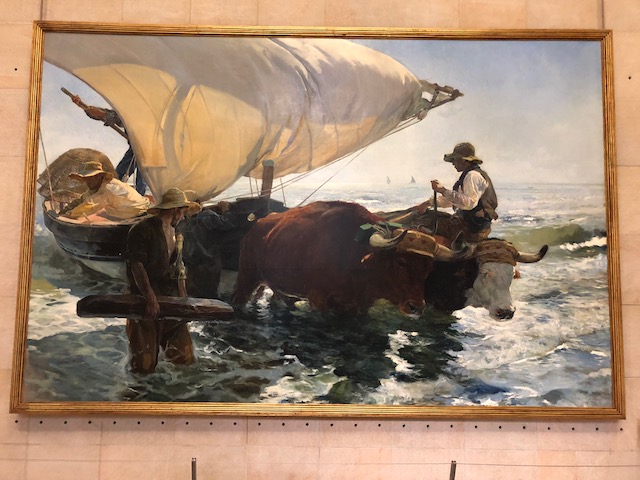 Large painting of an ox pulling a boat to shore, men on either side of it