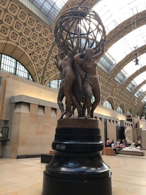 Tall bronze sculpture at the end of the center aisle, 3 men holding up a globe