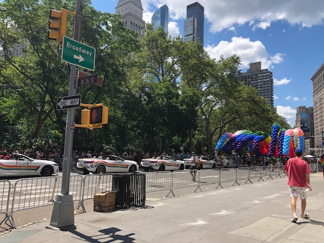 Street sign at 26th St & 5th Ave with a huge balloon arrangement up front, and vehicles participating as grand marshal behind it