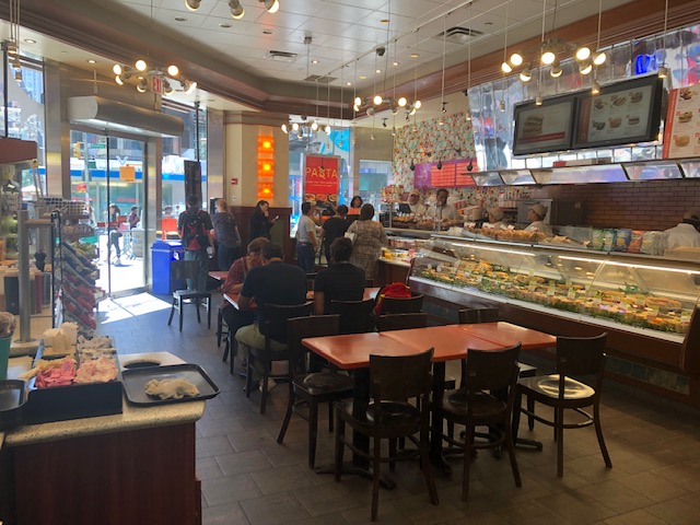 The dining area of Europa Cafe, with the workers behind a refrigerated food case
