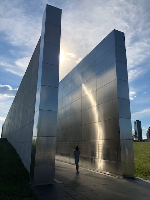 The 9/11 Memorial from an angle. Two polished steel walls creating an alley; the names of those who died engraved at eye height all along the length, probably 100 feet long; walls about 3 feet thick, maybe 25 feet high, 15 feet a part