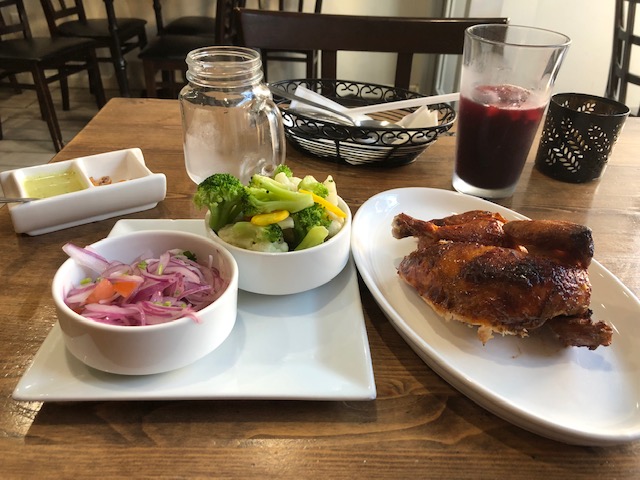 1/2 a chicken, steamed vegetables (broccoli, cauliflower, carrots, yellow zucchini) and an onion salad; with a juice drink in the background