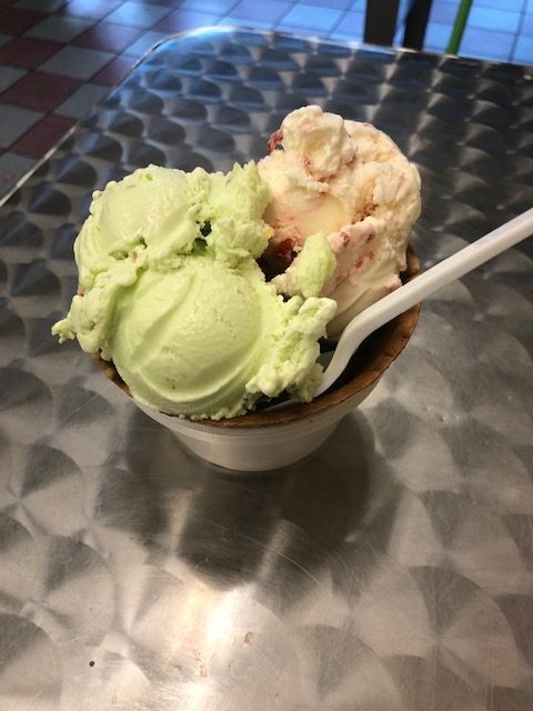 Pretty scoops of ice cream, one green, the other cream colored with cherries