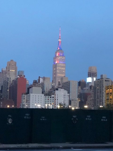 Top portioin of the Empire State Building lit in red, white and blue