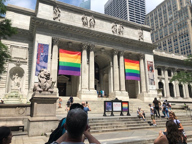 The New York Public Libray, with 2 large rainblow flags hanging between the front columns