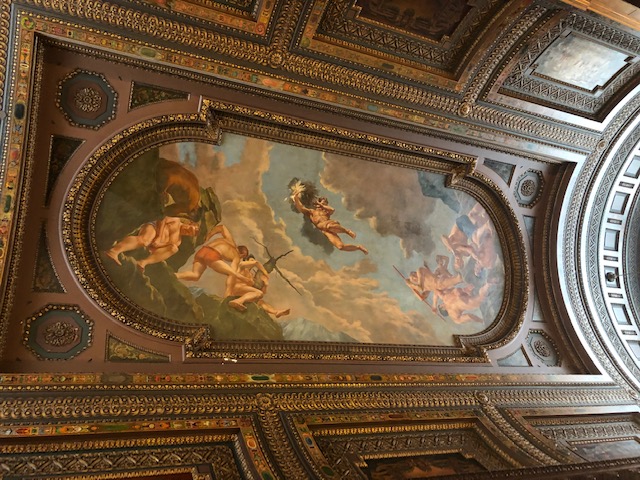 Ornate wood ceiling with a classical painting covering much of the center