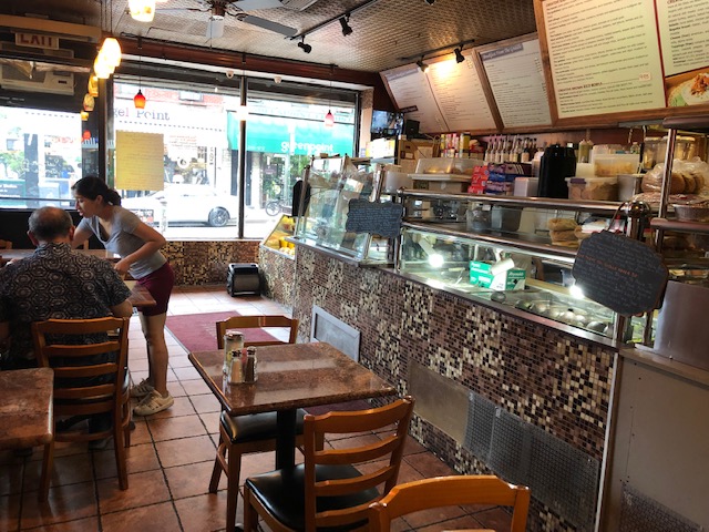 Inside of Lite Bites - counter/display/cashier on the right, 2 rows of 2 seat tables center and left