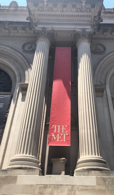 A tall banner with just the works The Met on it, in the middle of two columns, at the outside entrance