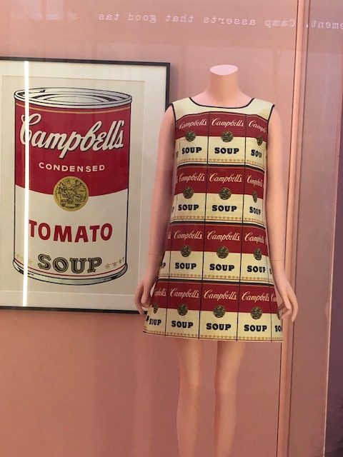Andy Warhol type painting of a Campbell's soup can; and a slim mini dress with the soup can image all over, 4 rows of them.