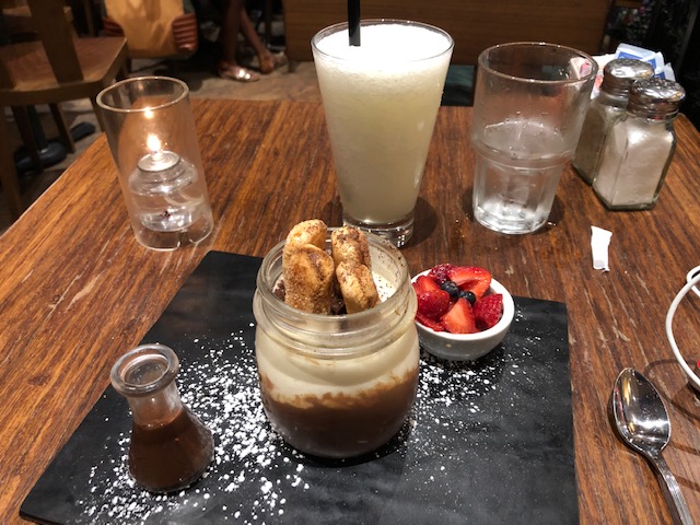 Tiramisu served in a preserving jar, with a tiny carafe of chocolate and small dish of fresh blueberries and sliced strawberries