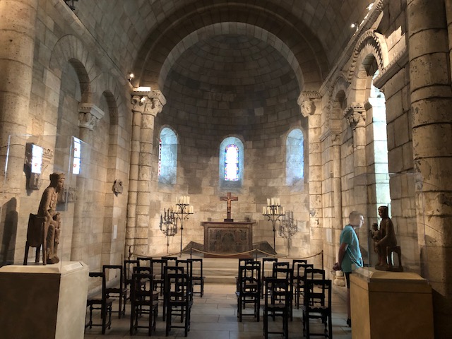 A small chapel with about 10 simple wooden chairs set up on each side of a narrow aisle