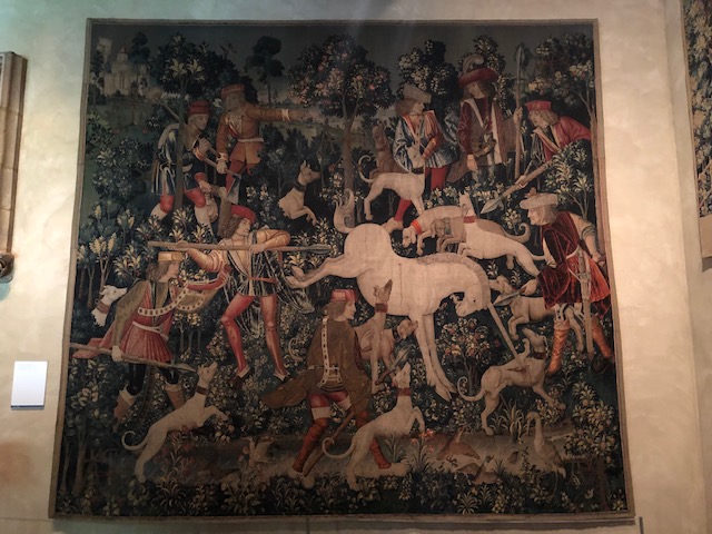 Tapesty of a unicorn fighting dogs, and men with weapons