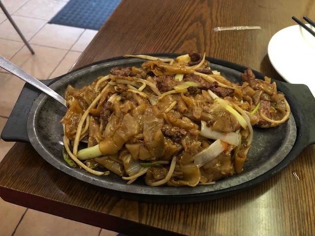 Sizzling spicy beef chow fun: beef, noodles, onions, peppers, served on a hot skillet