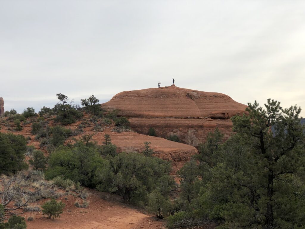 Because of the distance, two very small people standing atop a huge rock