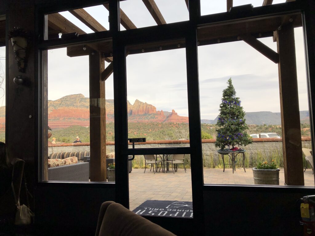 photo looks through glass doors and window onto the patio. There's a Christmas Tree there, with the mountains in the background