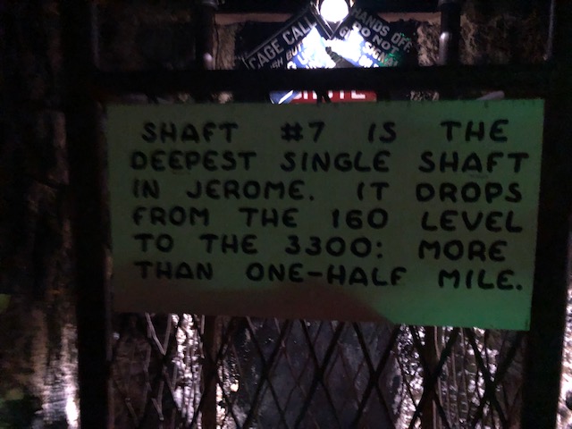 Sign says: Shaft #7 is the deepest single shaft in Jerome. It drops from the 160 level to the 3300: more than one-half mile