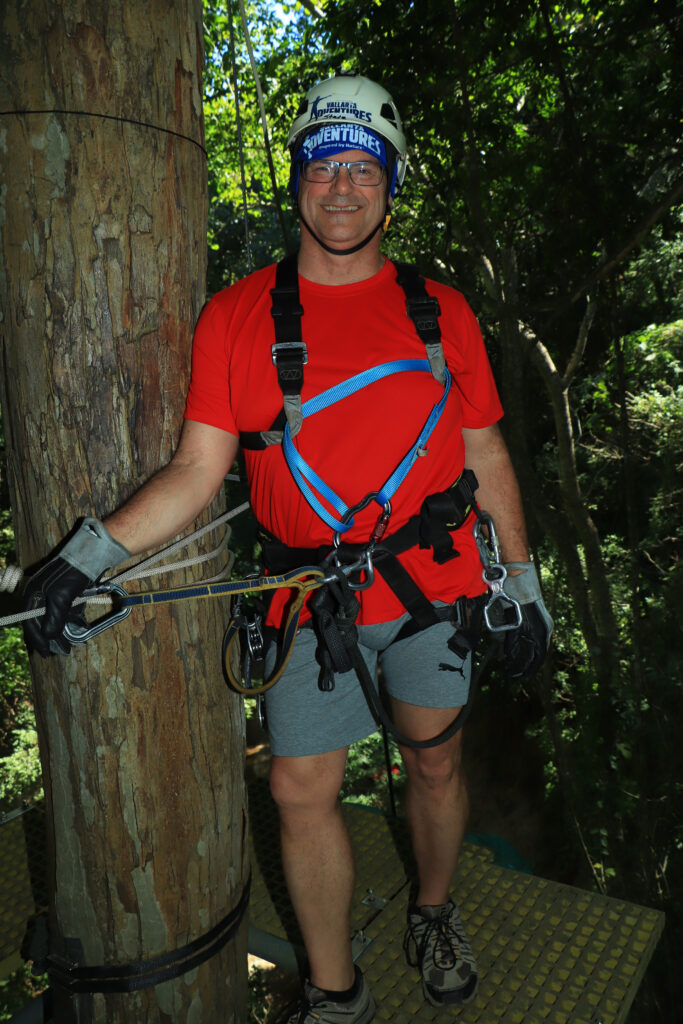 Me standing on a narrow platform around a tree, getting ready to zipline