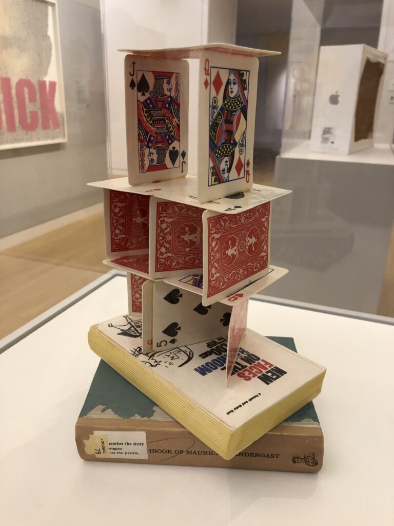A 3 layer house of cards on top of two books. 