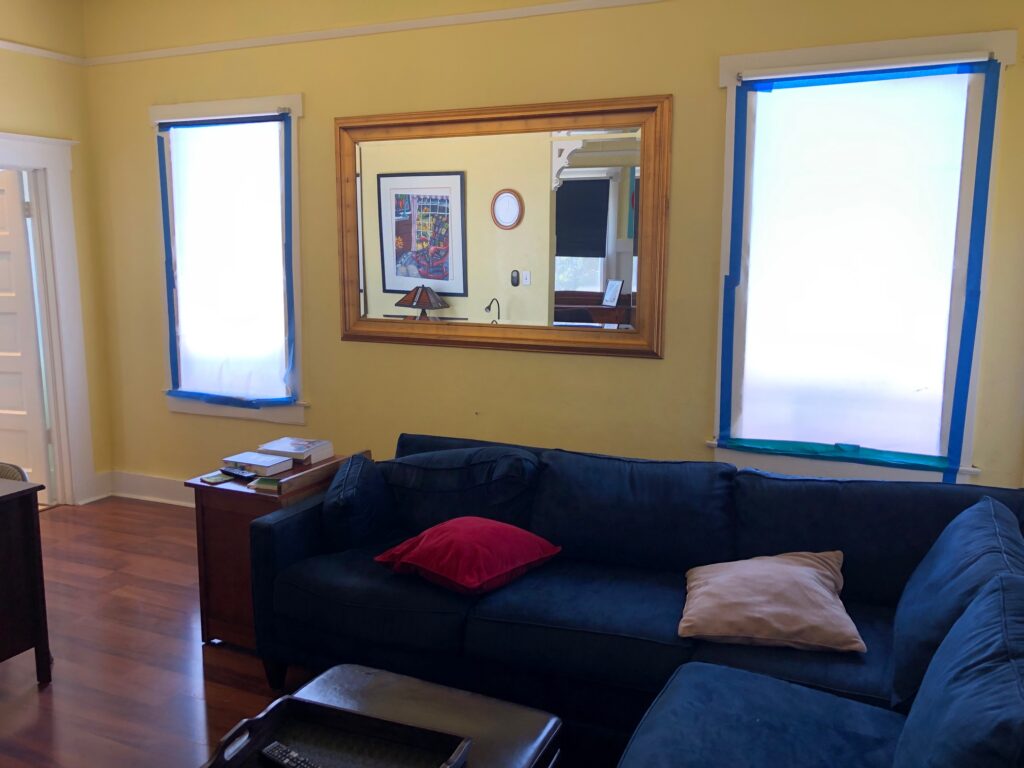 living room showing south windows covered with white paper, framed by blue masking tape - no windows