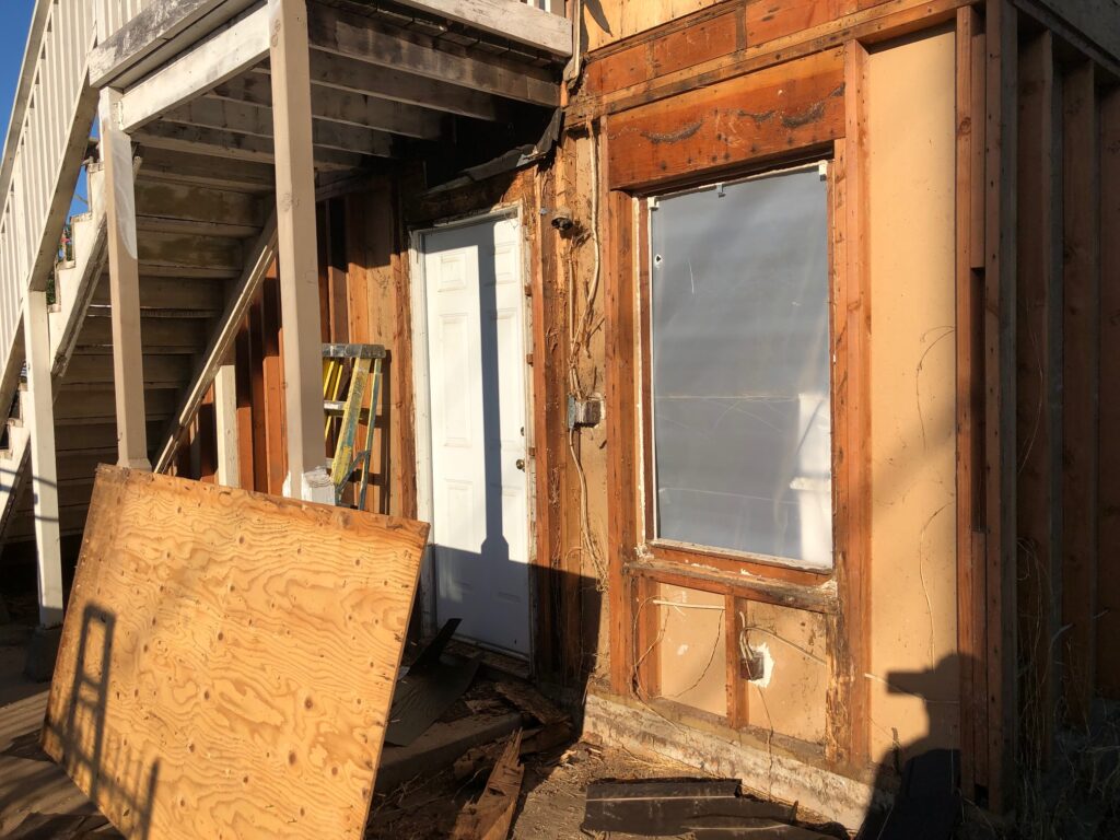 back of the house, back door of tenant unit, showing state of wood after siding off