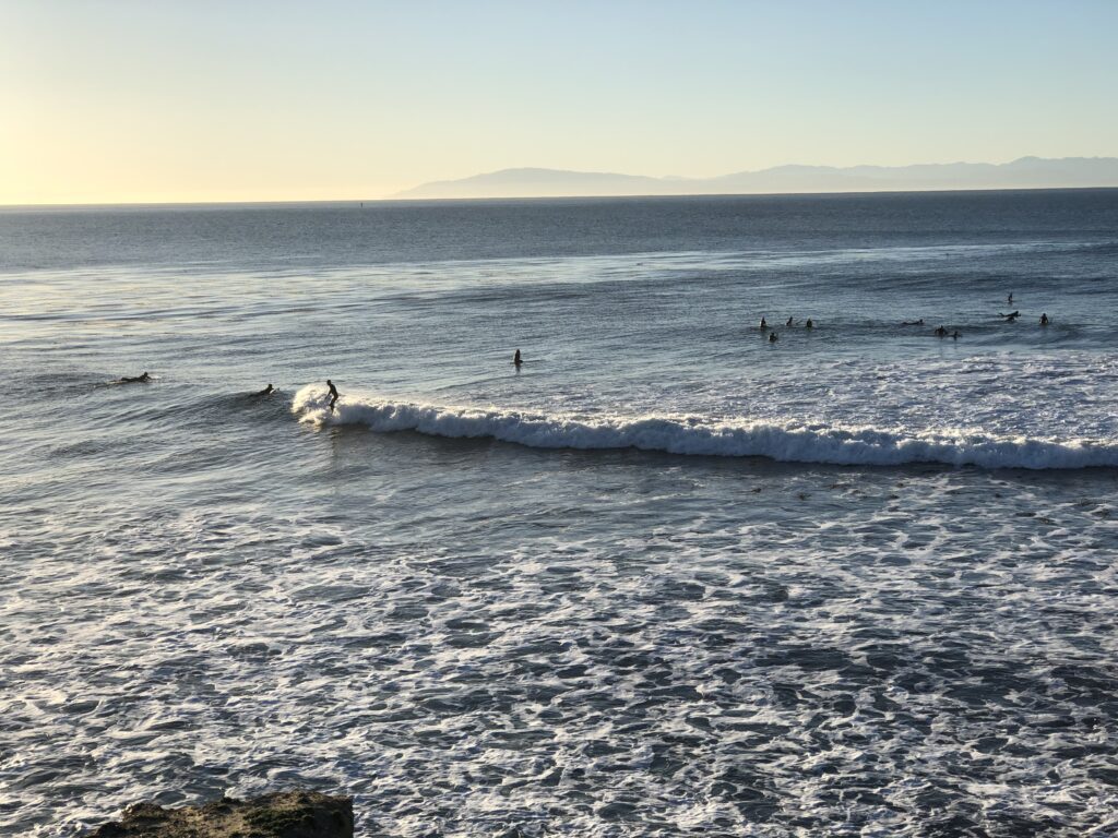 about 15 surfers in this shot, one of them riding a decent wave 