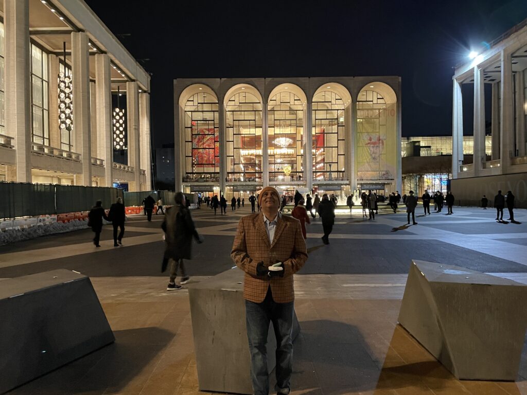 Ash at the beginning of the Lincoln Center Plaza, with a fountain and the opera hall far in the background. 
