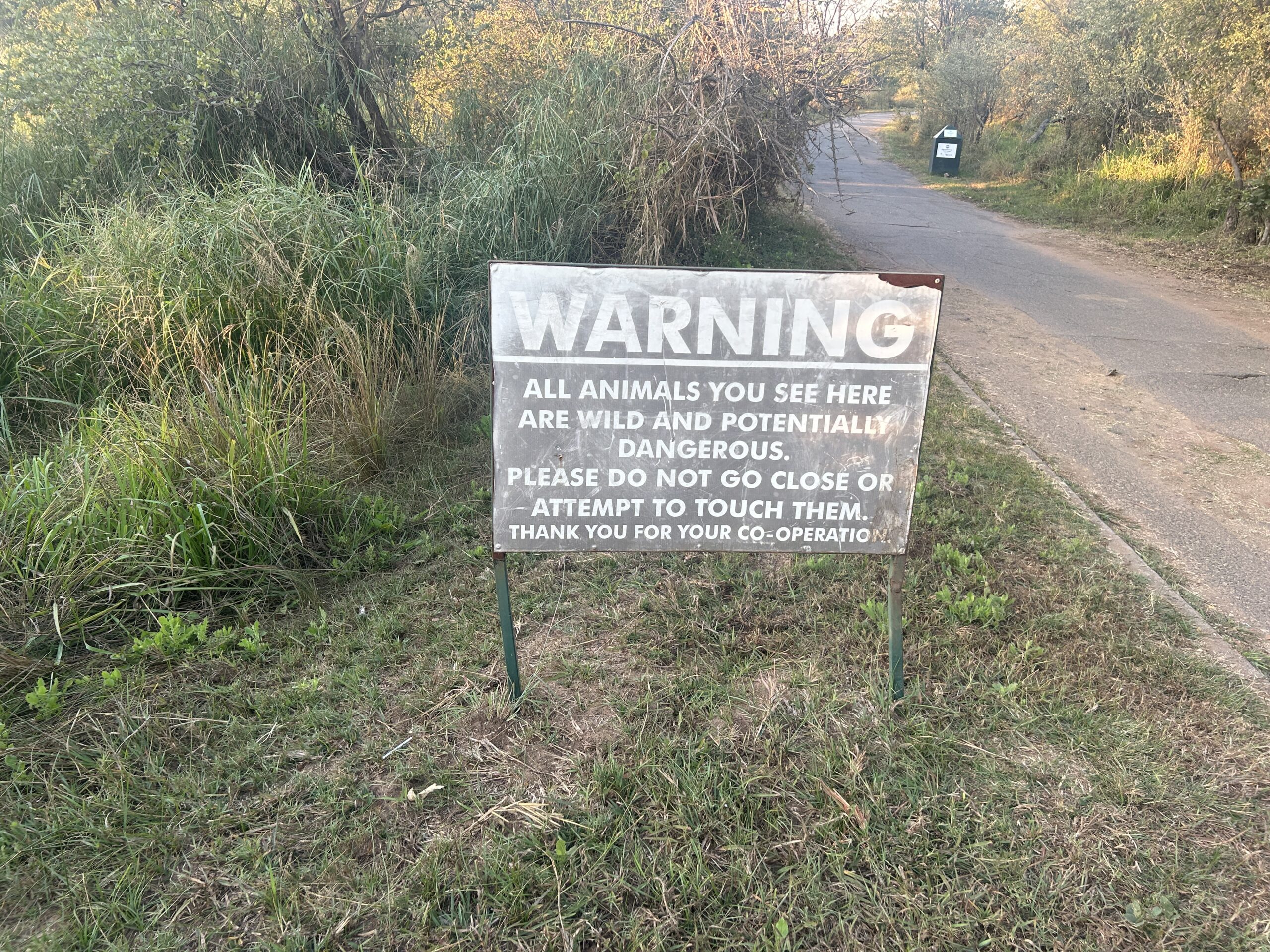 Sign on the side of the road: WARNING - all animals you see here are wild and potentially dangerous. Please do not go close or attempt to touch them. Thank you for co-operation. 