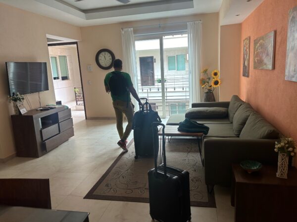 Photo of Ash walking about of the condo living room with luggage in tow. 