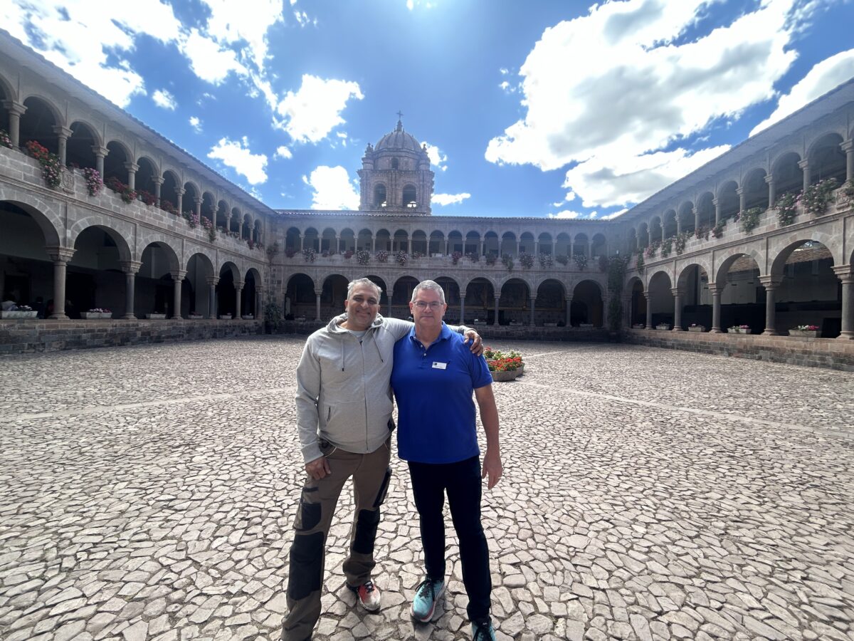 photo of us in the middle of a large courtyard, with columns and arches all around, and a flower garden in the middle behind us 